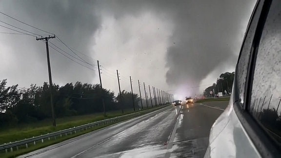 Eine Autobahn. Im Hintergrund ein Tornado. 