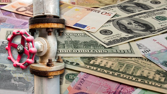 Geld in verschiedenen Währungen: Dollar, Euro und Rubel sowie eine Erdgasleitung