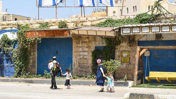 Jüdische Siedlerfamilie geht durch eine vormals palaestinensische Straße
