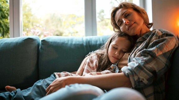 Mutter und Tochter sitzen kuschelnd auf dem Sofa