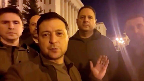 Wolodymyr Selenskyj steht mit anderen Männer auf der Straße in Kiew