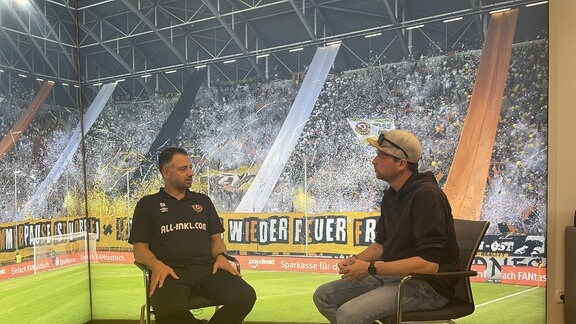 MDR-Reporter Benjamin Jakob im Gespräch mit Dynamo Dresdens Mannschaftsarzt Onays Al-Sadi (v.r.)