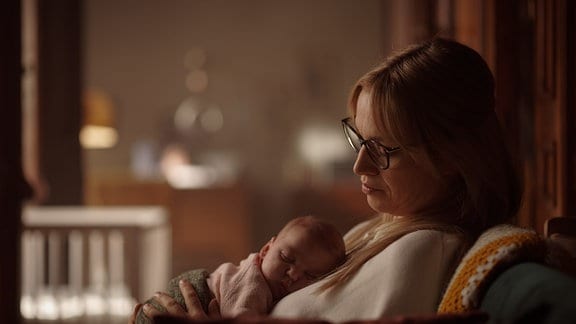 INGA WERNER (Franziska Hartmann) im Sessel sitzend mit dem entführten Säugling in ihrem Arm.