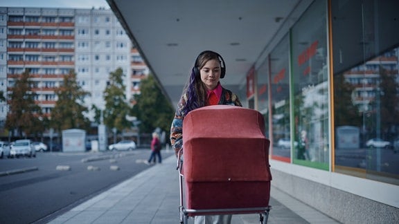LANA STOKOWSKY (Hannah Schiller) geht mit ihrem Säugling im Kinderwagen spazieren. 