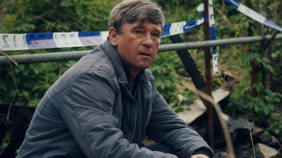 Polizeiruf 110 - Der Dicke liebt Michael Lehmann (Peter Schneider) ermittelt am Tatort, einer Kleingartenanlage.