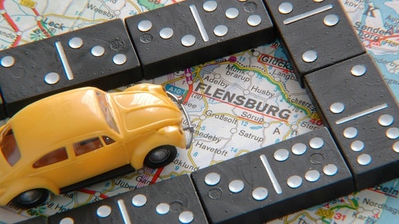 Dominosteine und Spielzeugauto auf einer Autokarte von Flensburg