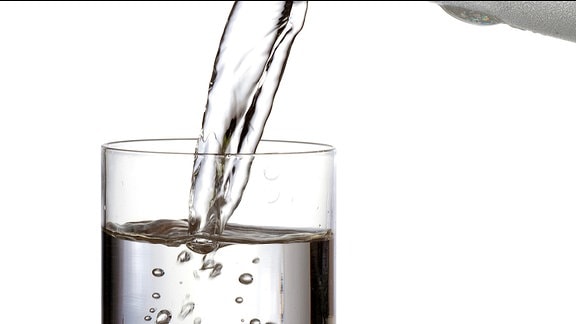 Wasser wird aus einer Glaskanne in ein Glas gegossen