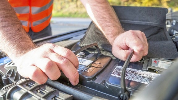 Ein Mann kontolliert eine Autobatterie.