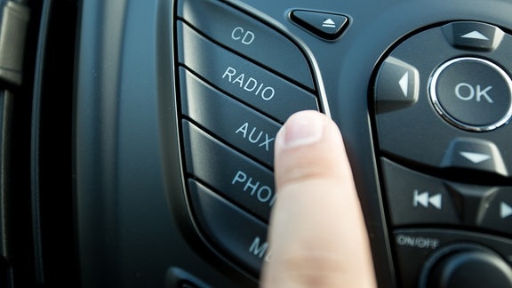 Ein Finger auf der Taste Radio in einem Auto