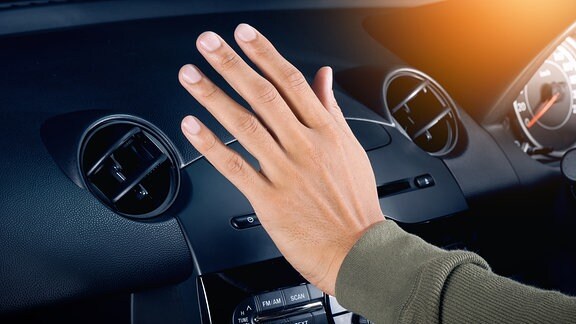 Eine männliche Hand fühlt den Luftzug einer Autoklimaanlage