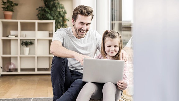 Junger Mann und kleines Mädchen, die zusammen im Internet surfen.