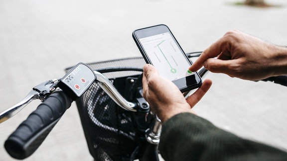 Mann mit E-Bike nutzt Navigationssystem auf Mobiltelefon.