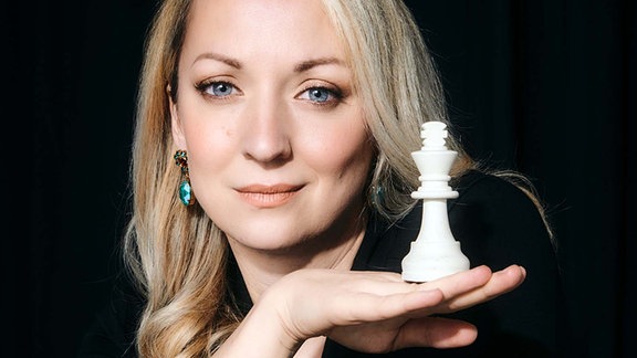 Schachspielerin Elisabeth Pähtz balanciert eine Damen-Spielfigur auf ihrem Handrücken.
