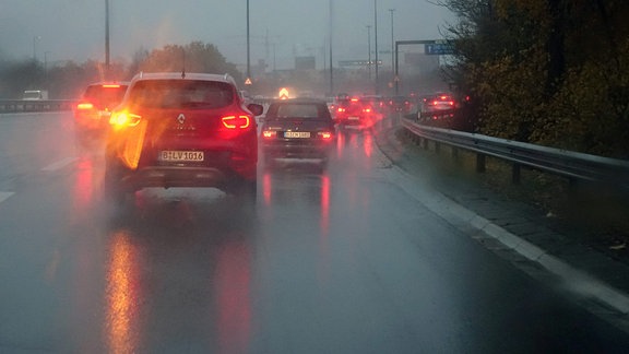 Auto blinkt bei Regen auf der Fahrbahn.