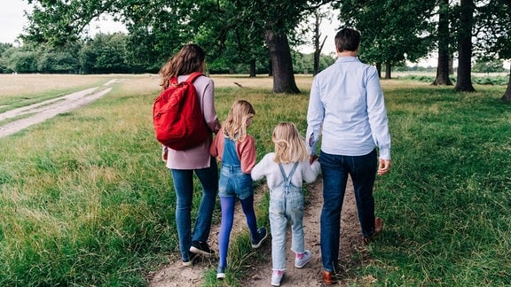 Eine Familie mit zwei Kindern geht in der Natur spazieren