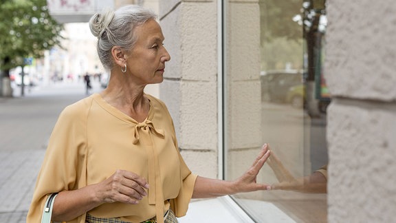 Ältere Frau vor einem Schaufenster.