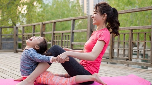 Eine chinesische Mutter und Tochter beim Yoga im Freien.
