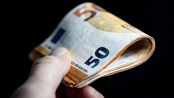 Eine Hand hält ein Bündel 50-Euro-Scheine.