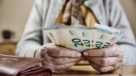 Hand einer Seniorin mit Euroscheinen