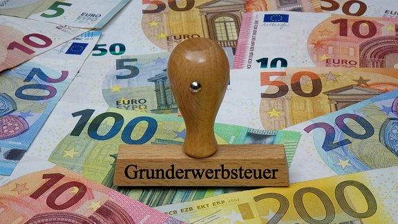 Geldscheine und Stempel mit Grunderwerbsteuer