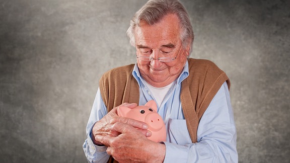 Ein älterer Mann hält eine Spardose.