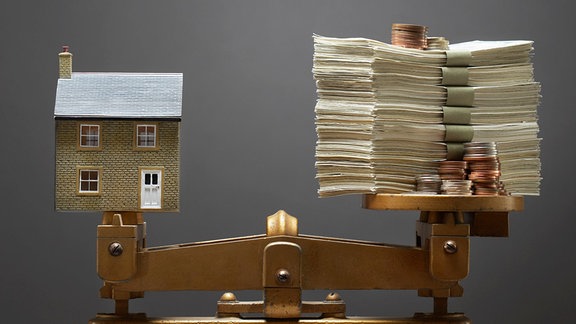 Modellhaus und Geld auf einer Waage
