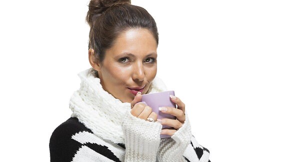 Eine Frau mit Pulswärmern und einer Tasse Tee