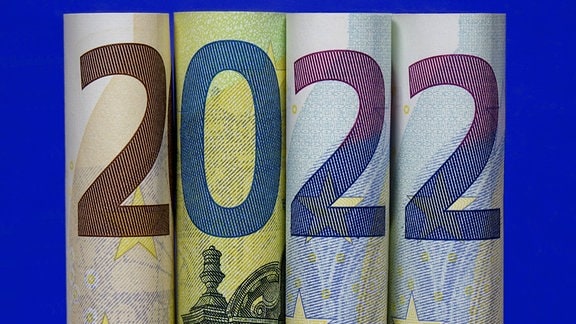 Zusammengerollte Geldscheine formen die Jahreszahl 2022.