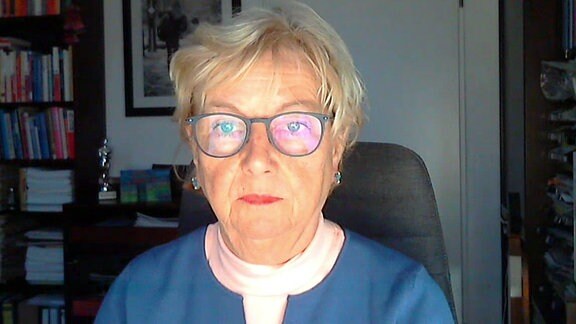 Eine Frau mit Brille und kurzem Haar sitzt vor ihrem Computer.