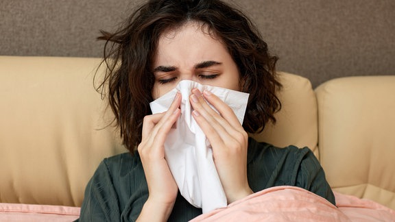 Frau mit Grippe liegt im Bett