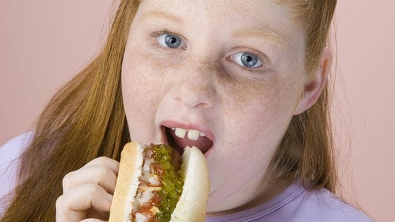 Ein Mädchen isst einen Hotdoc.