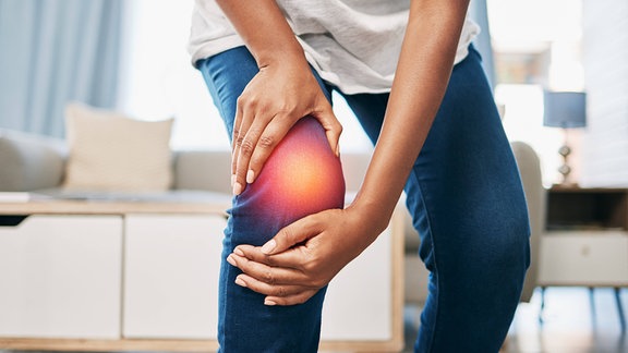 Symbolbild für Knieschmerzen: Eine Person fasst sich an das schmwerzende Knie.