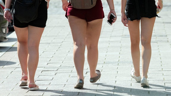 Junge Frauen mit Übergewicht gehen in gewagten, ultrakurzen Hot Pants áuf einem Fußweg.