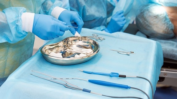 Die Hand eines Arztes hält ein Instrument im Operationssaal. Instrumente für eine Operation in einer sterilen Box.
