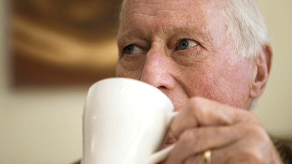 Ein älterer Mann trinkt aus einer Tasse