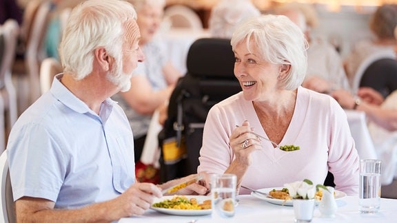 Ein Seniorenpaar sitzt zum Essen an einem Tisch
