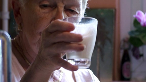 Seniorin hält gefülltes Glas