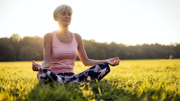 Eine Frau meditiert in einem Park