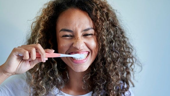 Eine junge Frau putzt sich die Zähne.