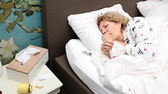 Frau liegt mit Grippe im Bett