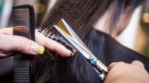 Eine Friseurin beim schneiden von aufgespaltenen Haaren (Spliss)