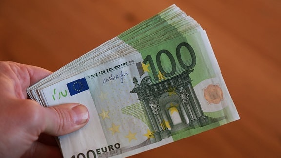 Eine Hand hält ein Bündel Hundert-Euro-Noten