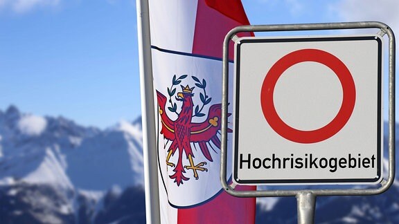 Hochrisikogebiet steht auf einem Schild vor der Flagge Österreichs.
