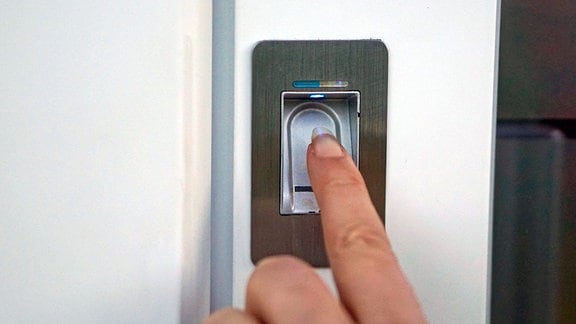 Ein Zeigefinger wird auf einen Fingerprint-Scanner an einer Haustür gelegt