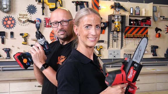 Ein Mann und eine Frau stehen mit Werkzeug in den Händen in einer Werkstatt