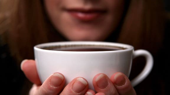 Eine Frau hält eine Tasse Kaffee.