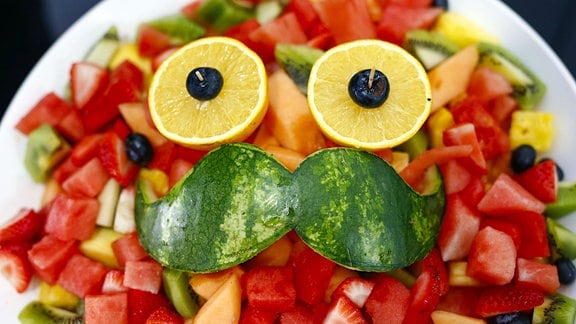Melonensalat in einer Schüssel mit einem Gesicht aus Schale und Zitronenscheiben.