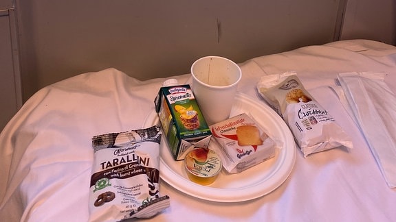Abgepacktes Frühstück auf einem Bett im Zug