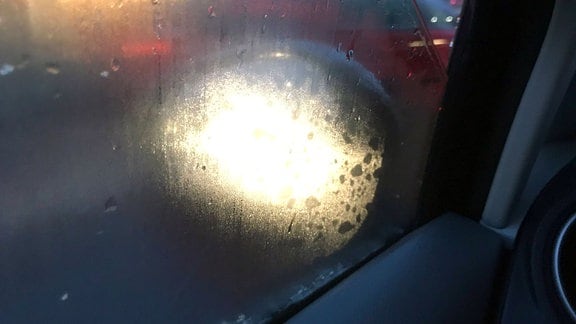 Die Sicht durch das beschlagene Seitenfenster eines Autos ist getrübt.
