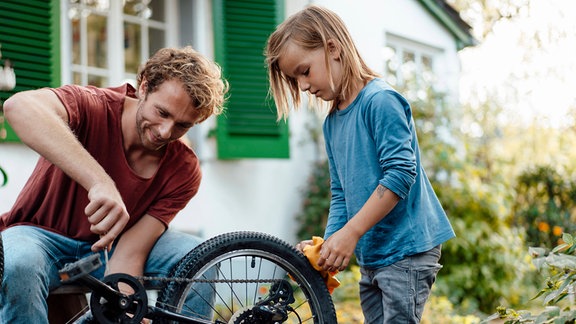 Vater und Sohn beim Reinigen und Reparieren von einem Fahrrad
